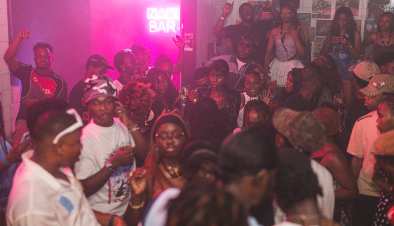 A red-lit room, dancers pressed up against the decks
